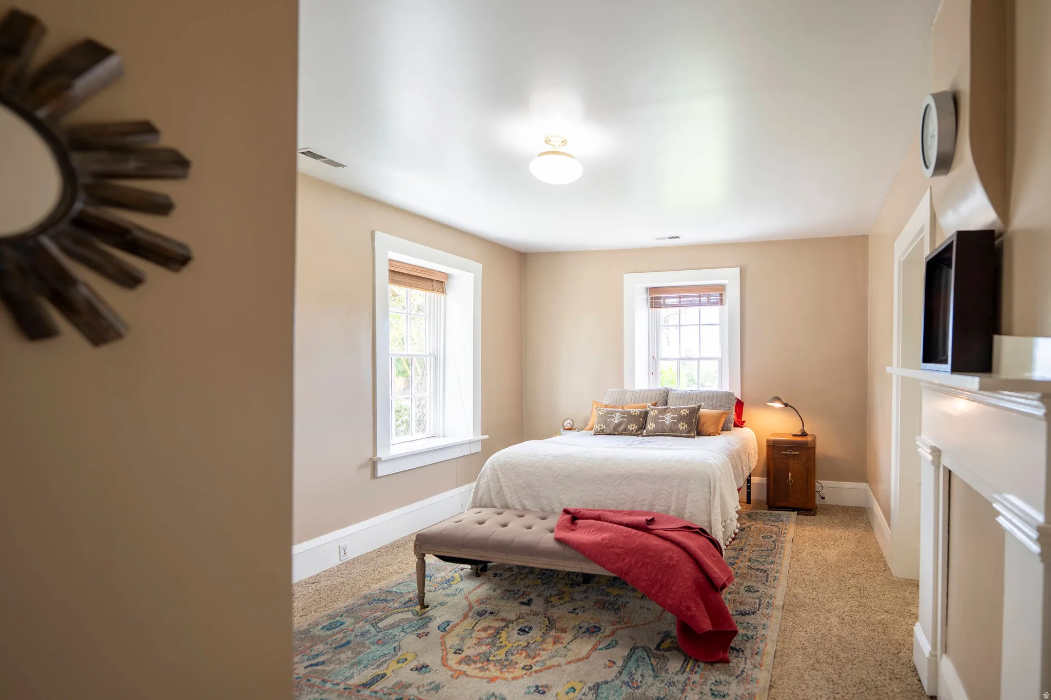 Bedroom featuring two windows with wood blinds, a ceiling-mounted light fixture, and neutral-toned walls