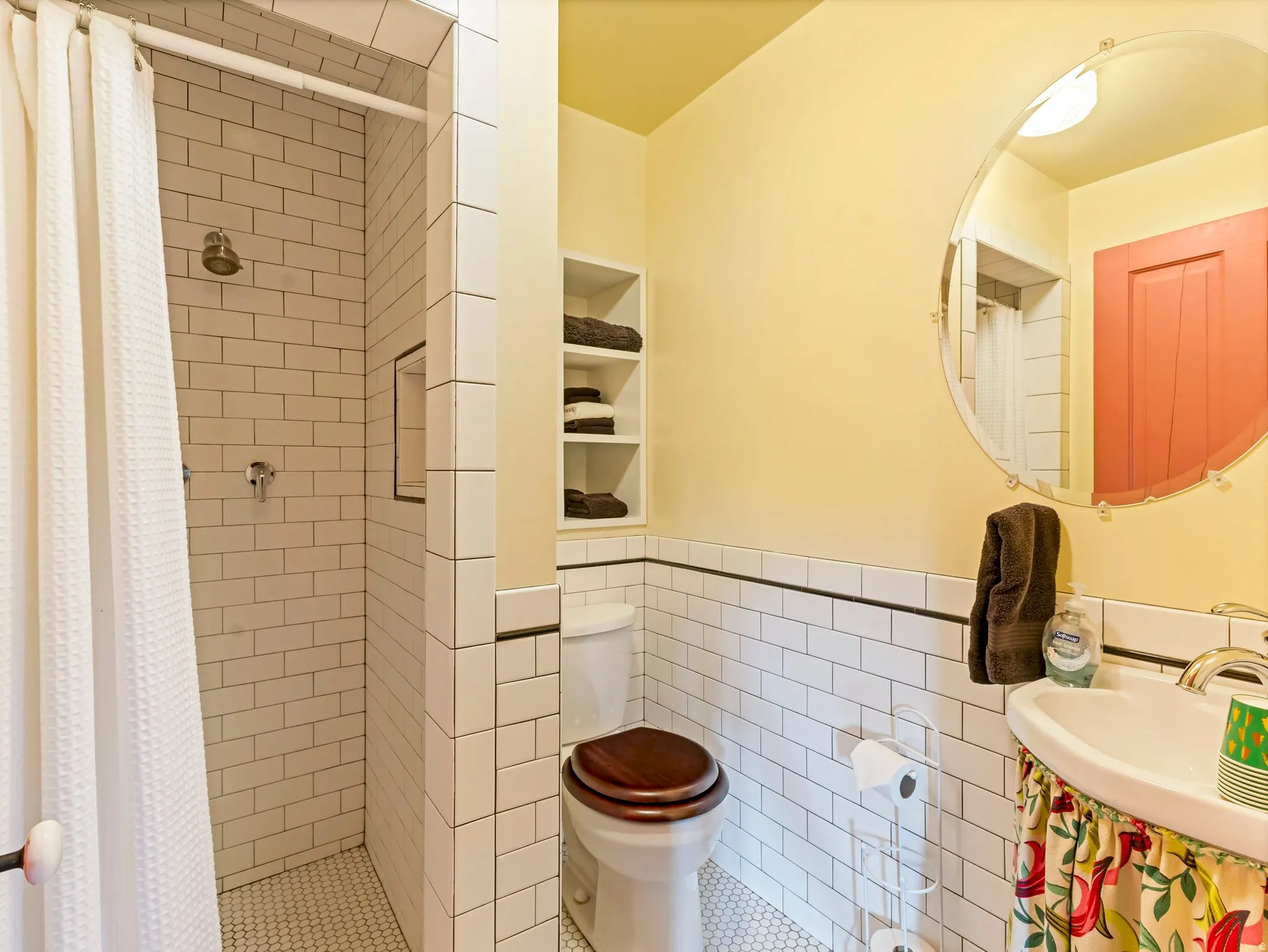 Bathroom featuring subway tile shower, hexagonal floor tile, recessed shower niche, built-in shelving, and a pedestal sink with chrome fixtures