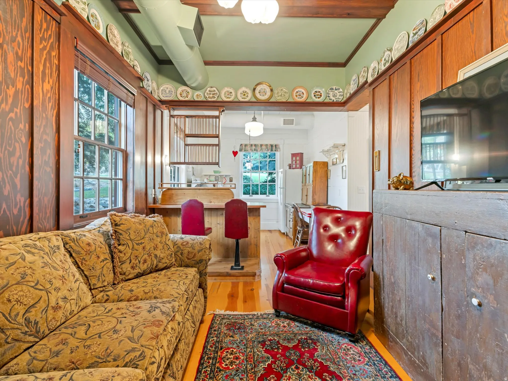 ADU living area featuring exposed wood ceiling beams, hardwood flooring, and a built-in entertainment cabinet