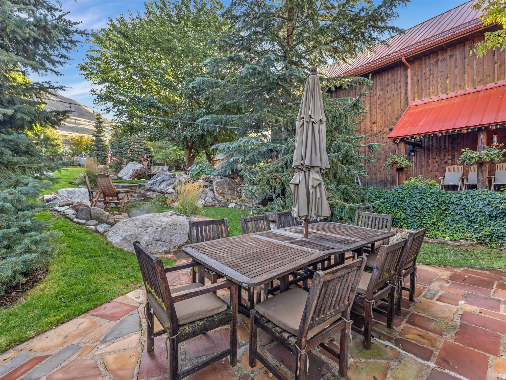 Expansive patio featuring multi-toned flagstone pavers and a garden area with diverse evergreen foliage