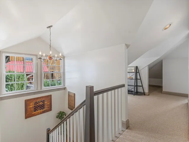 Carpeted upper hallway with vaulted ceilings and a recessed light fixture
