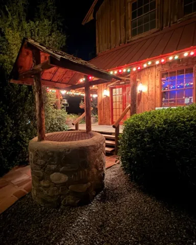Stone-clad well feature with a wood shingle roof, positioned on a gravel bed