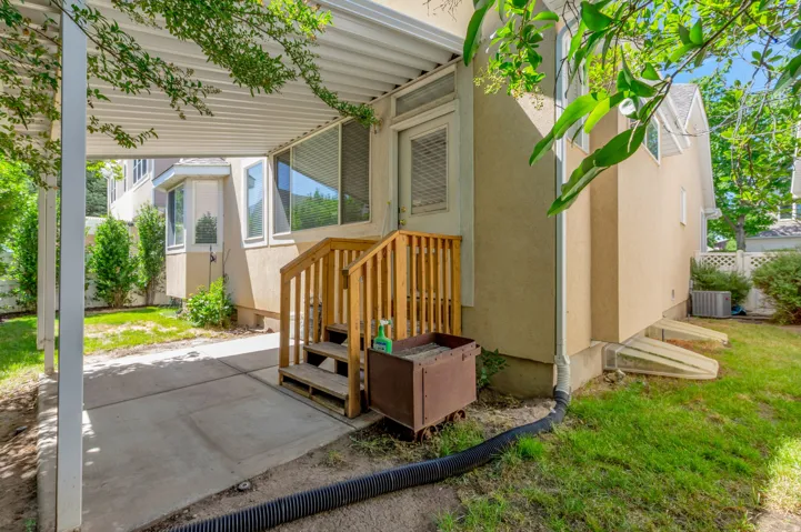 Covered patio featuring a concrete slab and wood stairs leading to a rear entrance