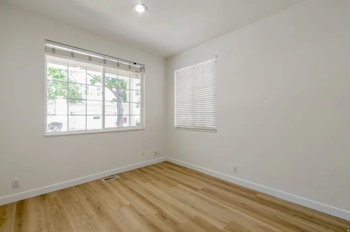 Room featuring wood-finish flooring, white baseboards, and neutral wall tones