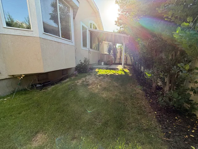 Rear exterior showcasing a covered patio with a wooden deck, bay windows, and stucco siding