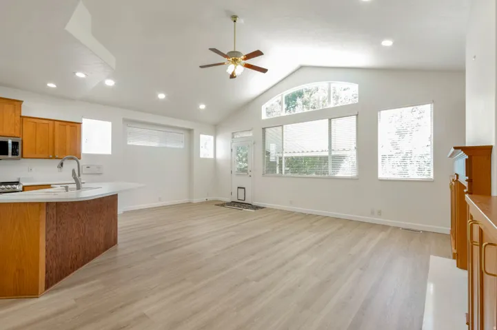 Spacious living area featuring vaulted ceilings, light wood-finish flooring, and recessed lighting