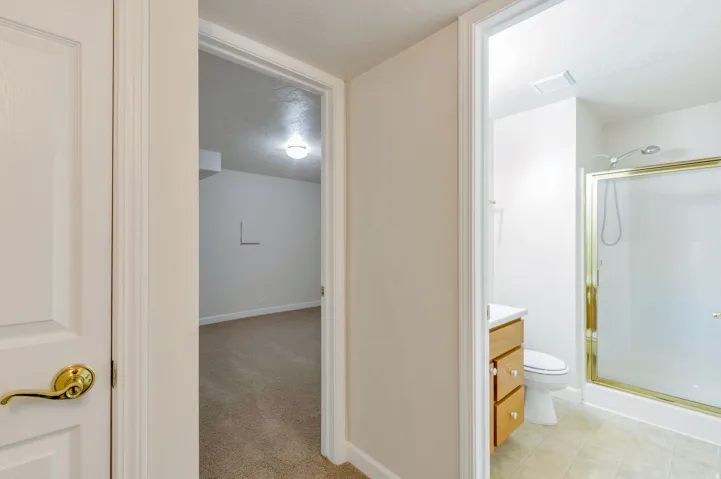 Bathroom featuring a glass-enclosed shower, light wood-finish vanity with a white countertop, and neutral tile flooring
