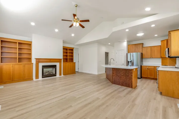 Open-concept living space featuring vaulted ceilings, recessed lighting, and light wood-finish flooring