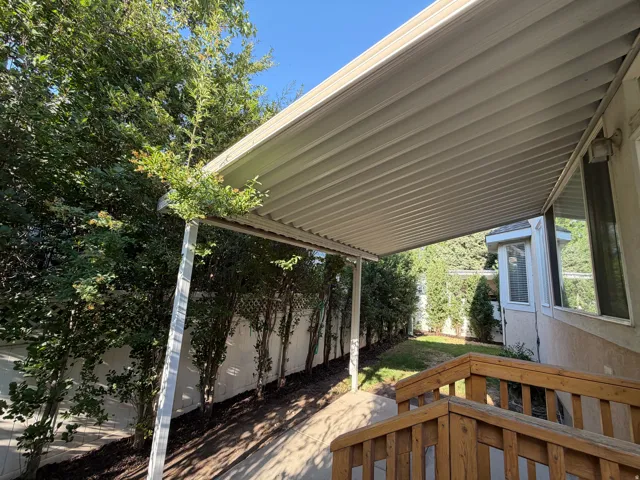 Expansive covered patio with a textured ceiling, supported by white metal posts
