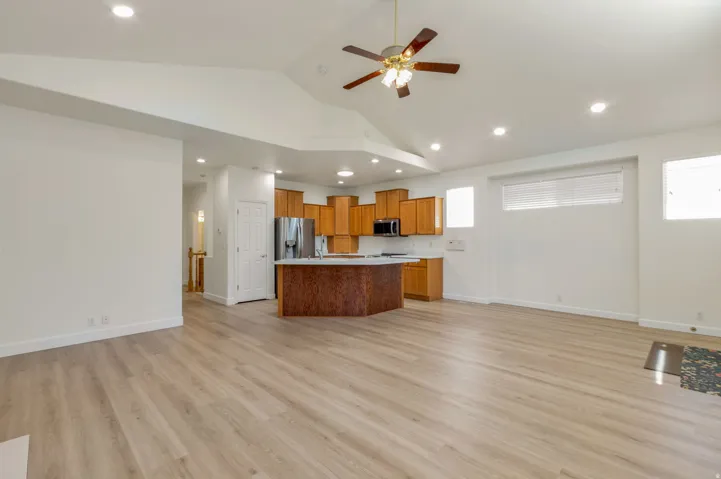 Open-concept living space featuring wood-finish flooring, recessed lighting, and a vaulted ceiling with a ceiling fan