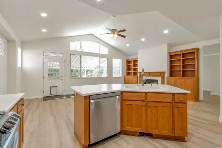 Kitchen featuring a central island with dual sinks, light-toned countertops, and stainless steel dishwasher