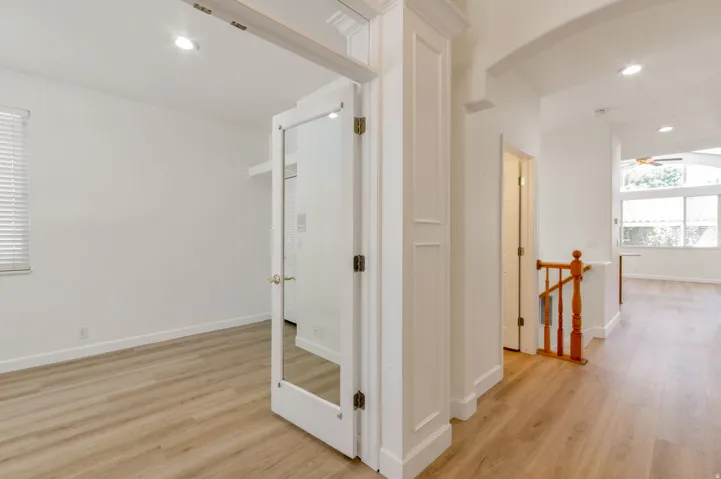 An interior room with wood-finish flooring and a window with blinds