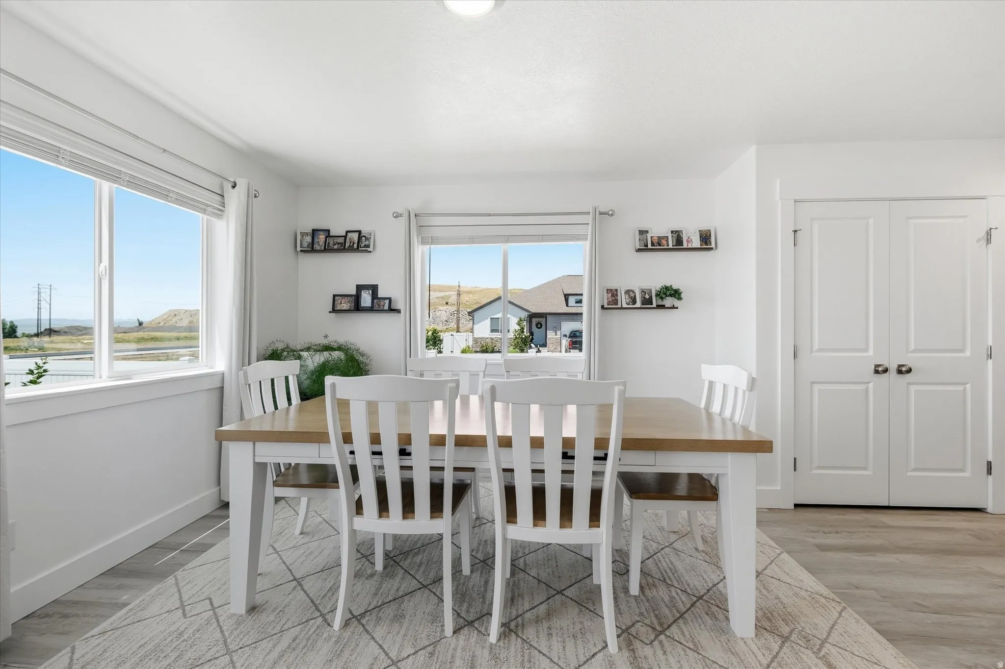 Dining area featuring light wood-finish flooring, white walls, and a pair of white paneled double doors