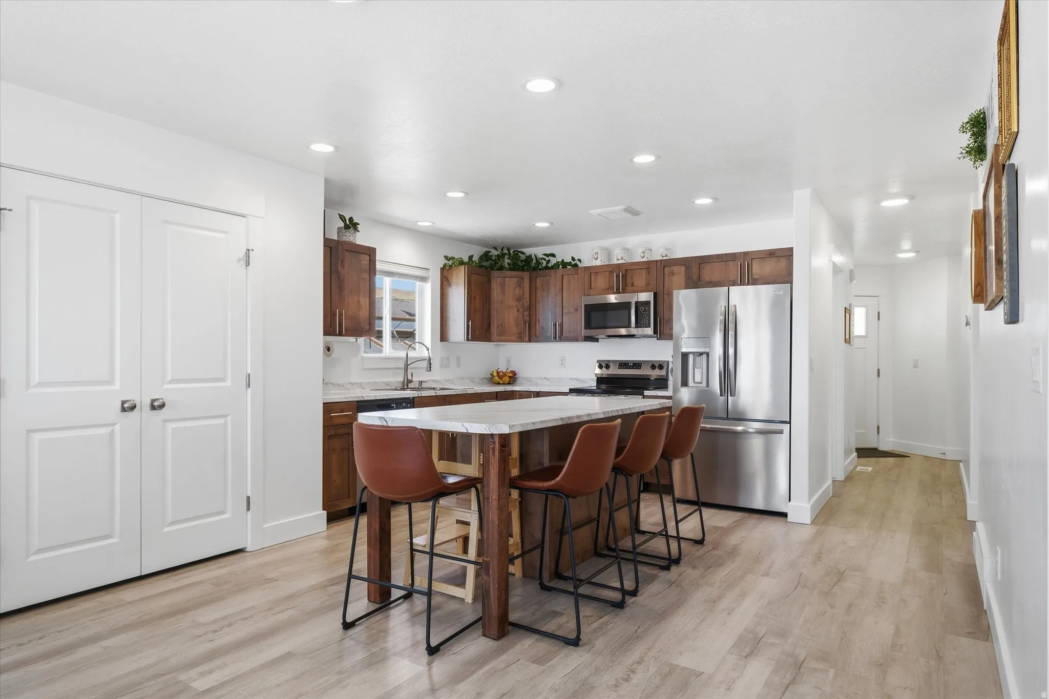 Open-concept kitchen featuring wood-finish flooring, recessed lighting, and a kitchen island with a light-toned countertop