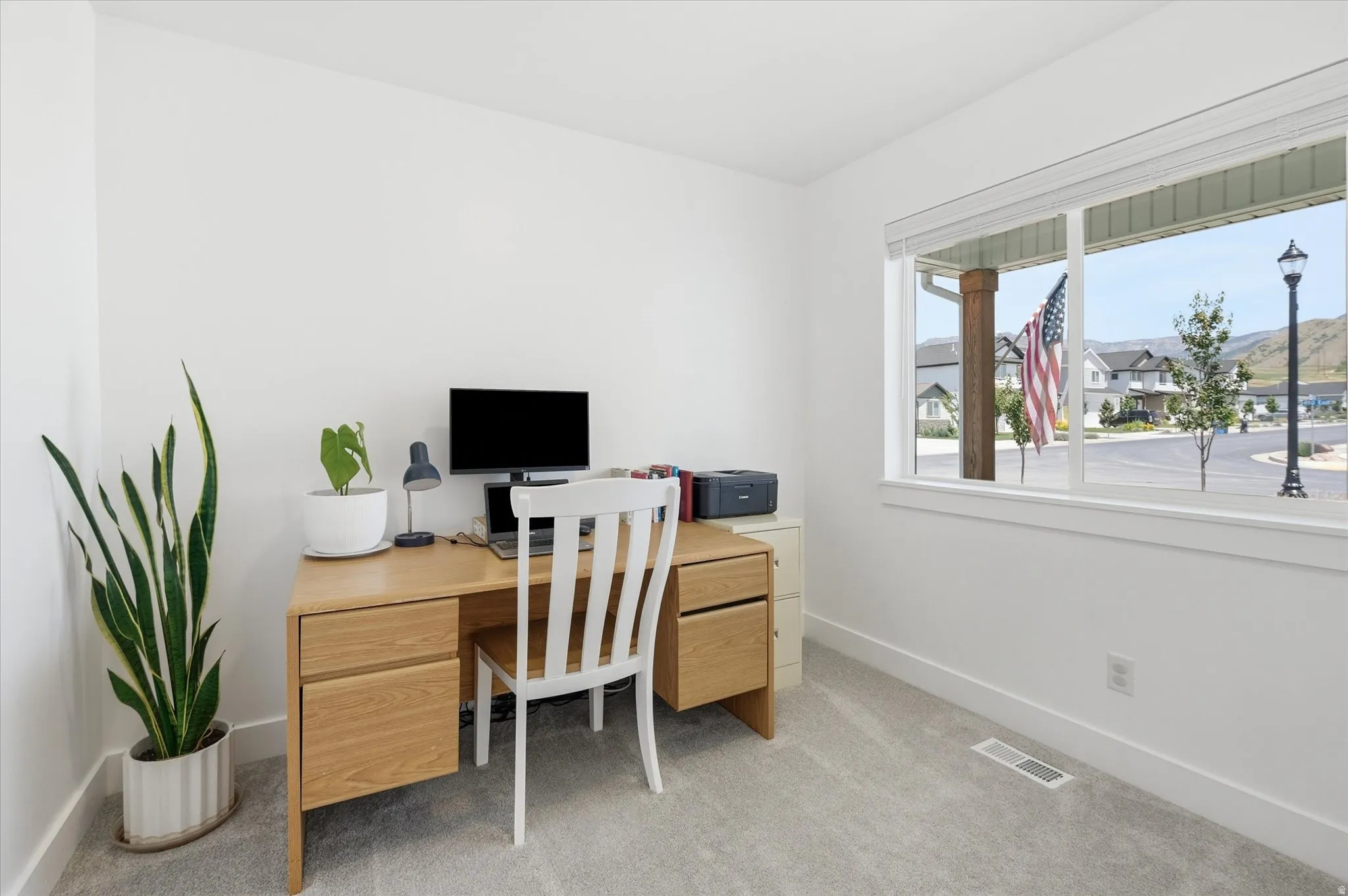 Bright room featuring a large window, plush carpet flooring, white walls, and white baseboards