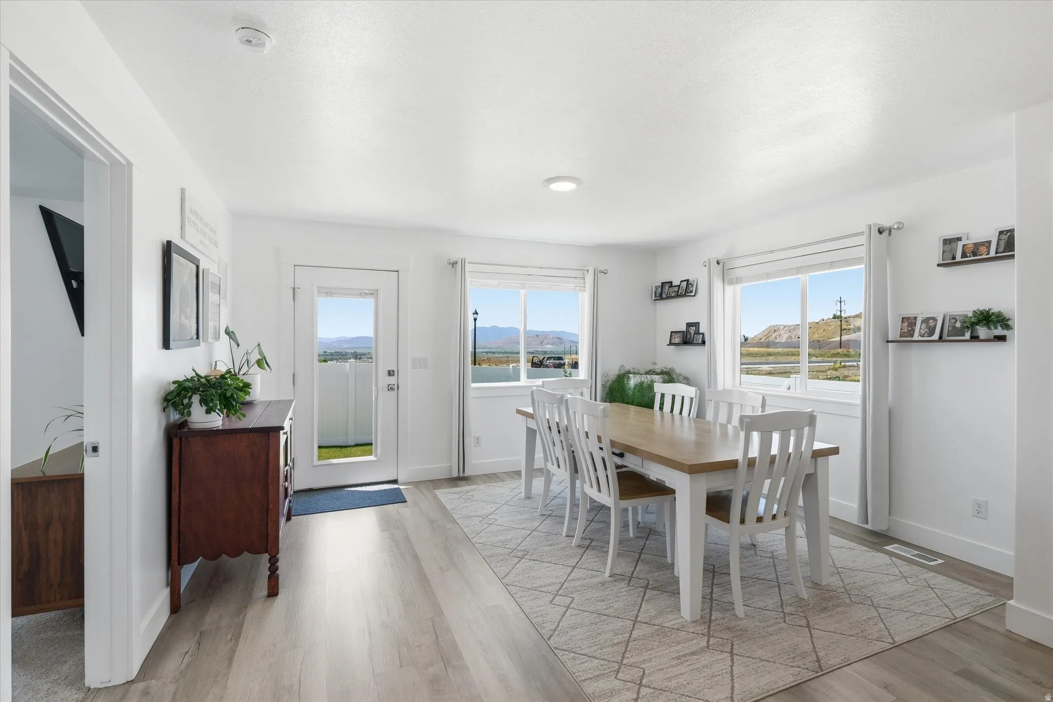 Spacious dining area featuring abundant natural light, light wood-finish flooring, white baseboards, and a glass-paneled exterior door