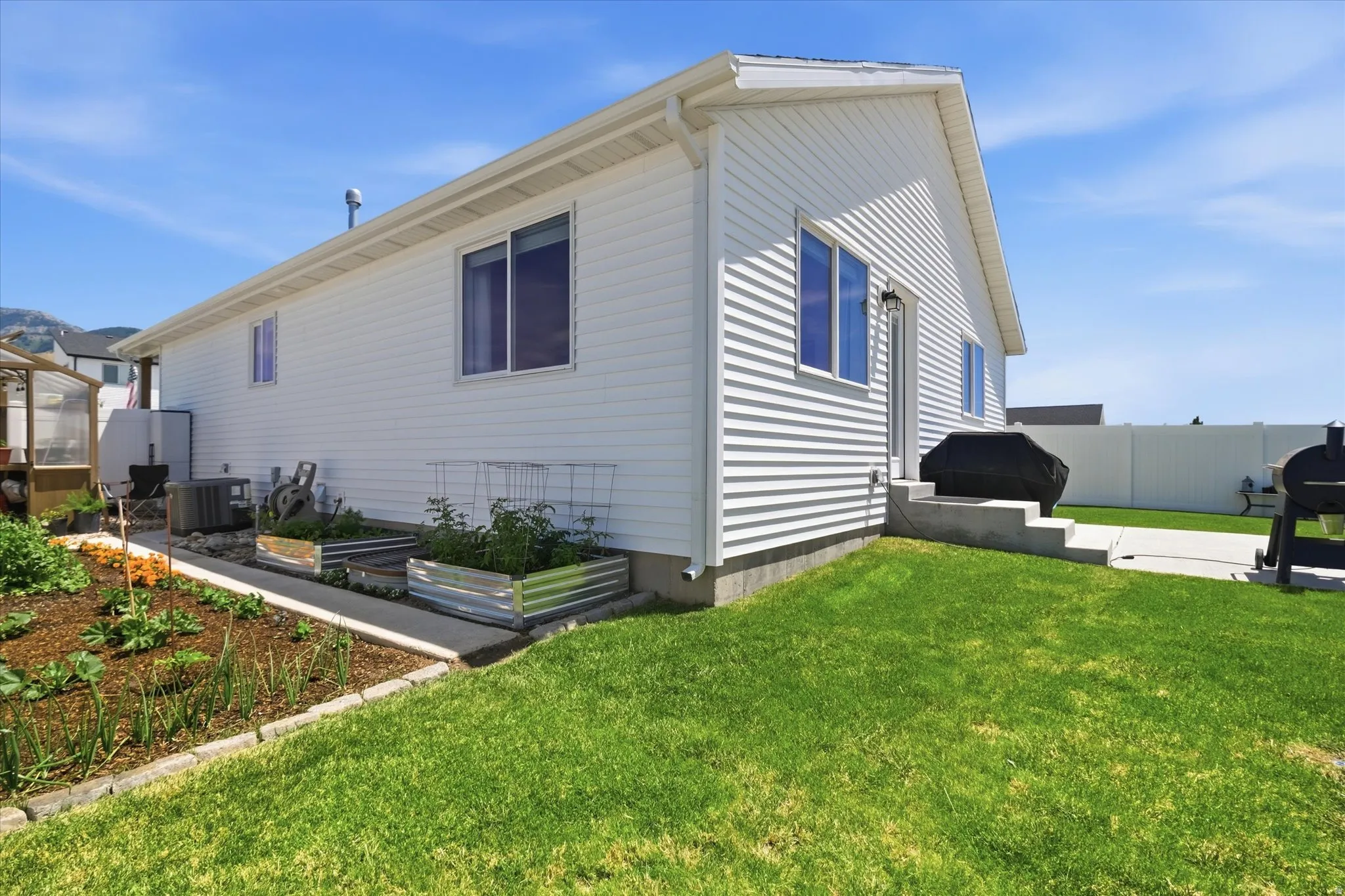 Rear exterior featuring white horizontal siding, a concrete patio, and a manicured lawn