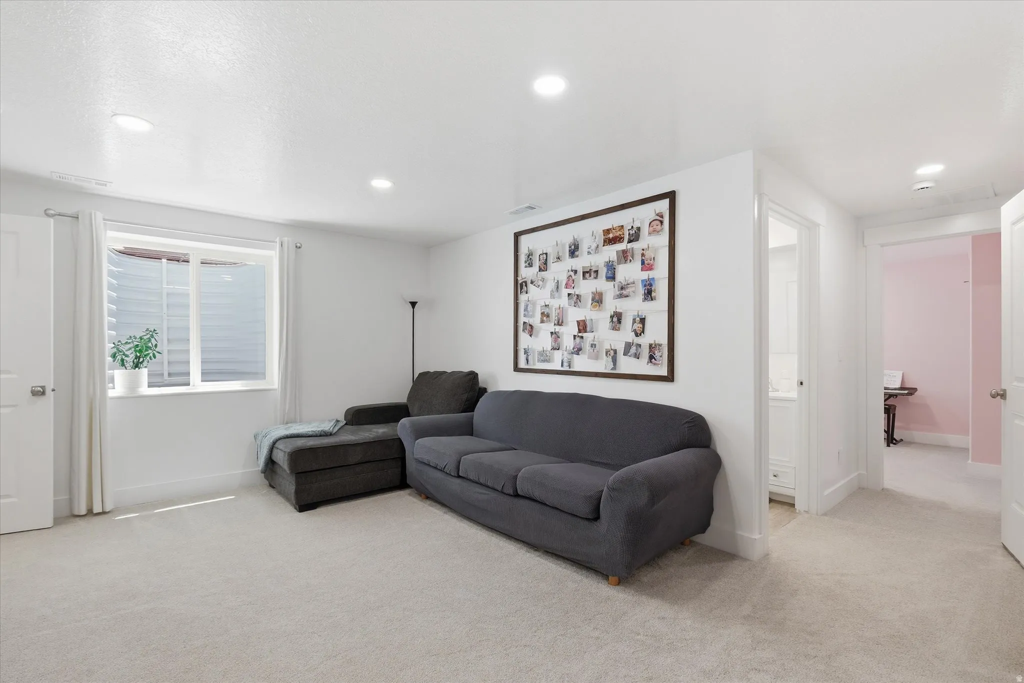 Spacious room featuring light-toned carpeting, recessed lighting, and a window with white trim