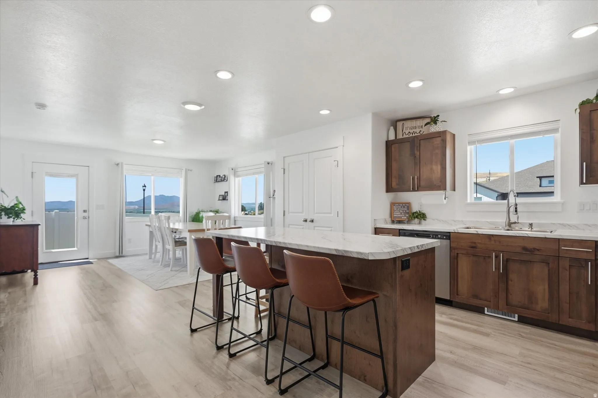 Open-concept kitchen and dining area featuring wood-finish flooring, recessed lighting, and white walls