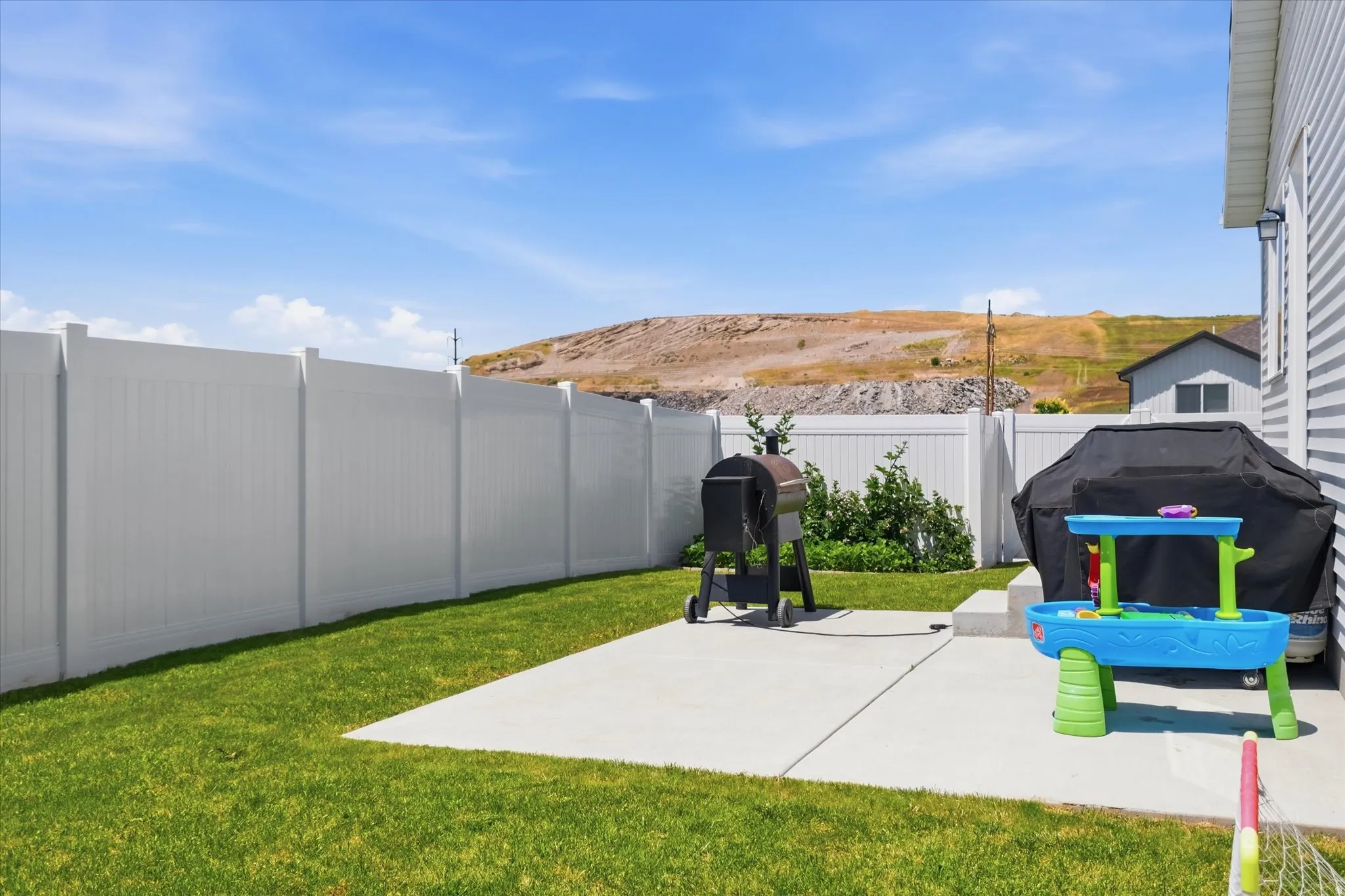 Expansive backyard featuring a manicured lawn, a large concrete patio, and full perimeter privacy fencing