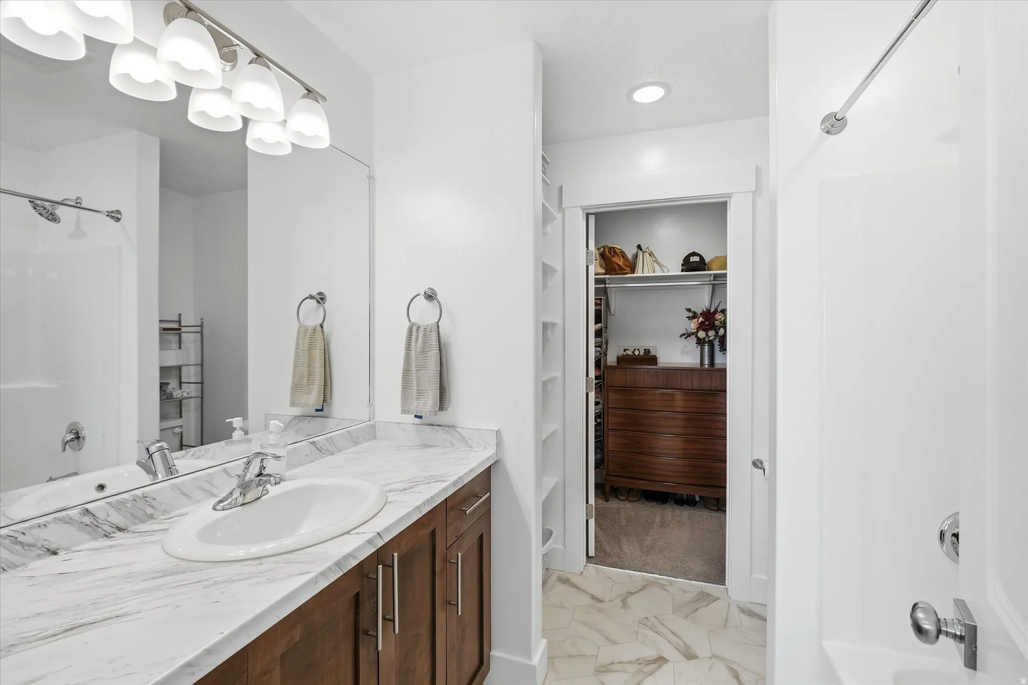 Bathroom vanity featuring a single-basin sink, a stone-finish countertop, and wood-finish cabinetry with brushed nickel hardware