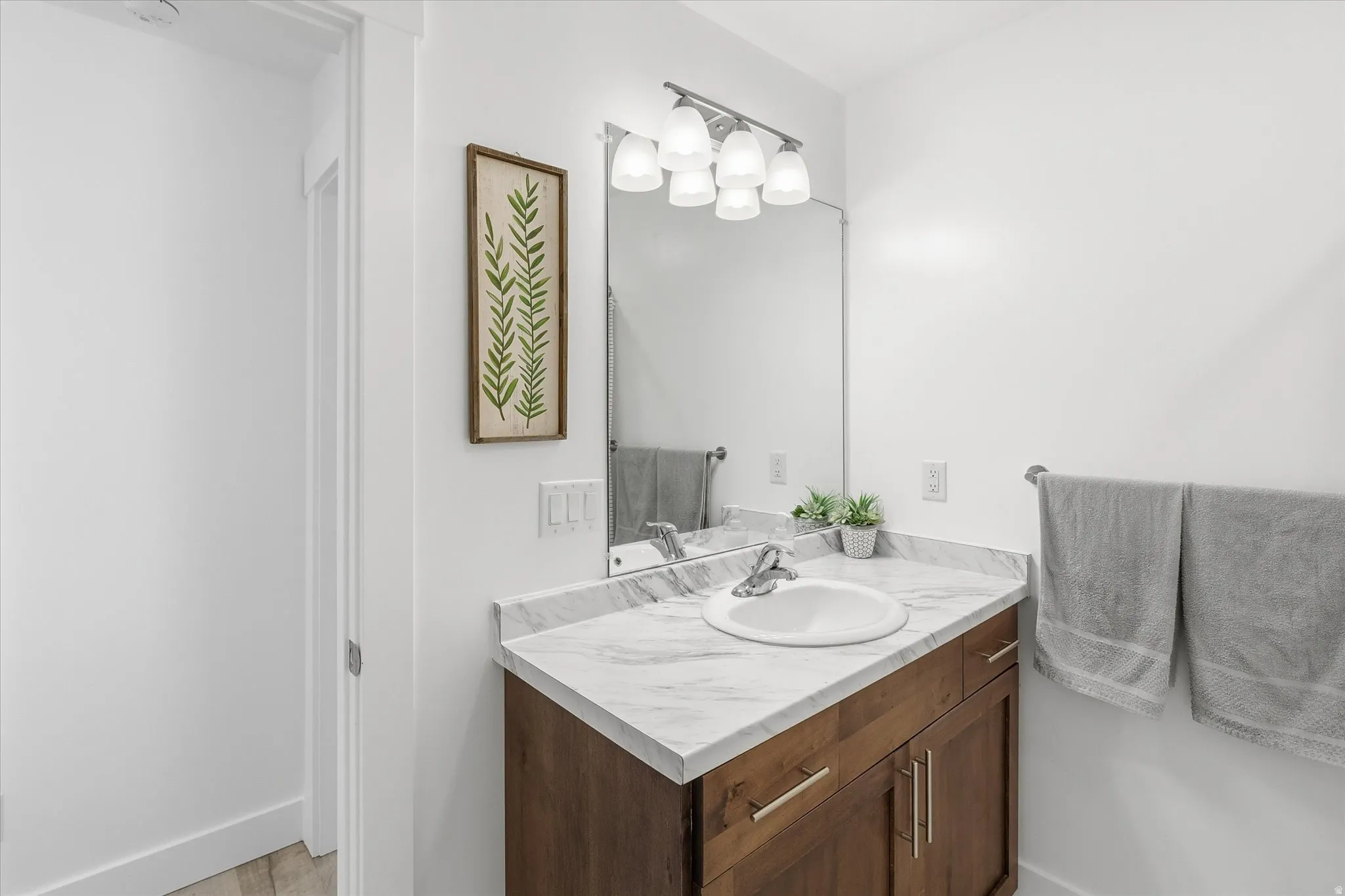 Bathroom vanity featuring a wood-finish cabinet, a white undermount sink, and a stone-finish countertop