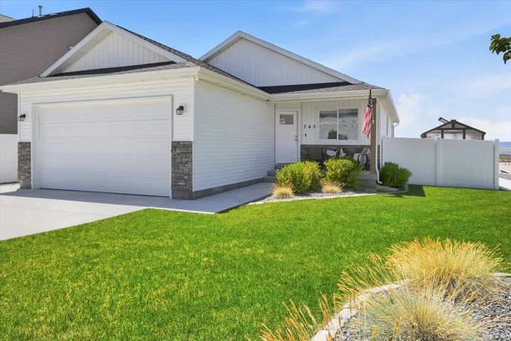 White siding exterior with stone accents, a two-car garage, and a covered porch entry