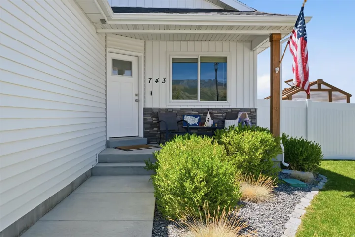 White horizontal siding exterior with a covered porch featuring a wood support column and stone accent wall
