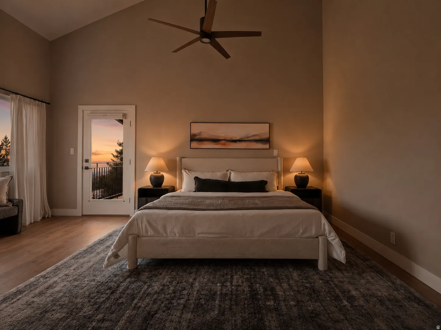 Vaulted ceiling bedroom featuring wood-finish flooring, a ceiling fan, and a glass-paneled door leading to an outdoor balcony with metal railings