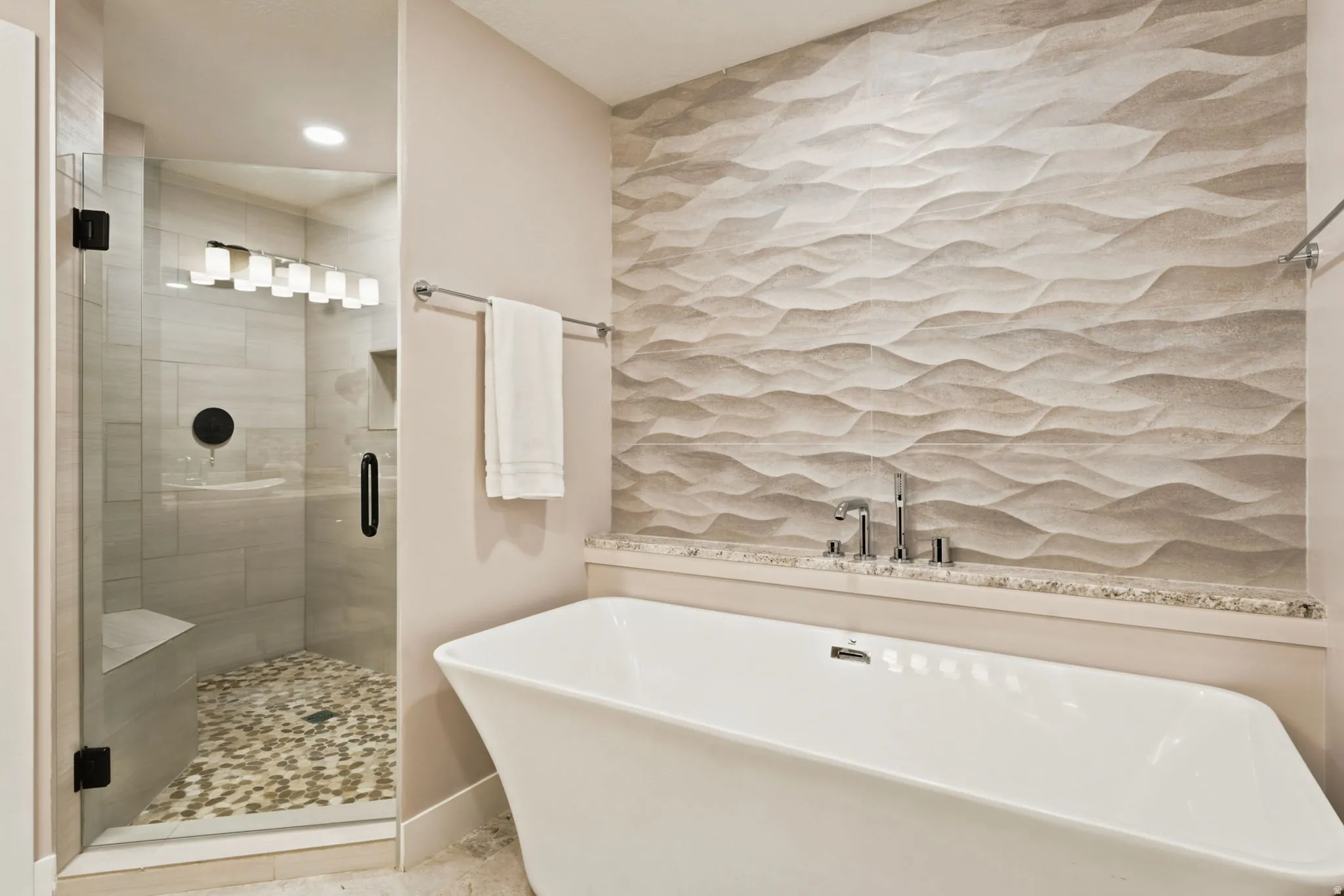 Freestanding soaking tub with a textured accent wall