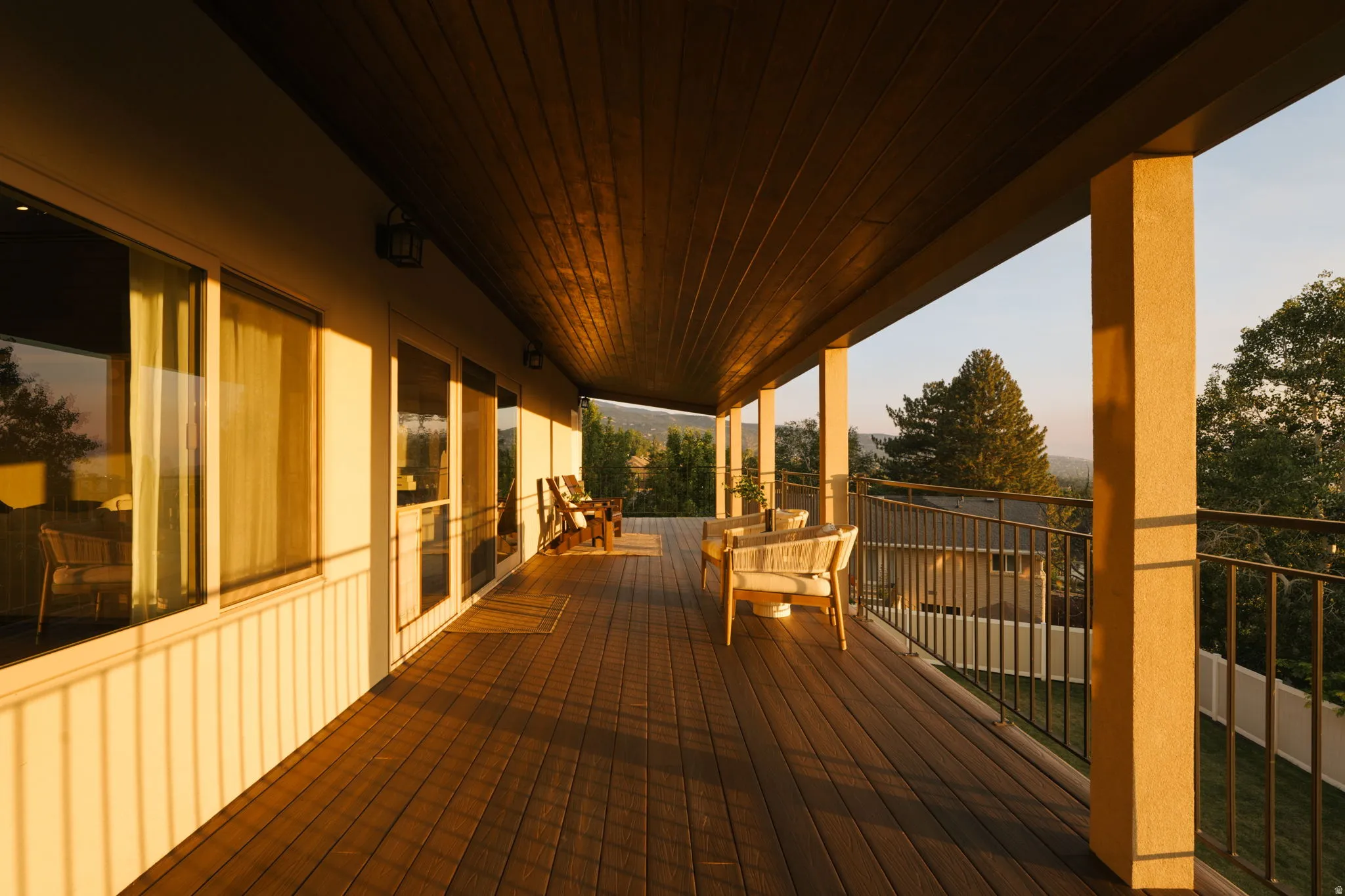 Expansive covered deck featuring wood-finish flooring, a wood plank ceiling, and stucco columns
