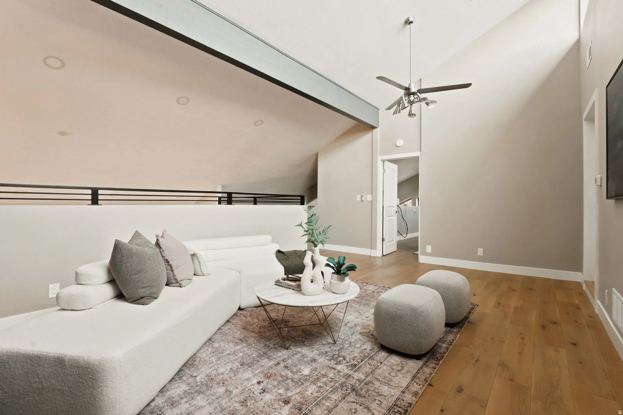 Living area featuring vaulted ceilings, wood-finish flooring, and a modern ceiling fan