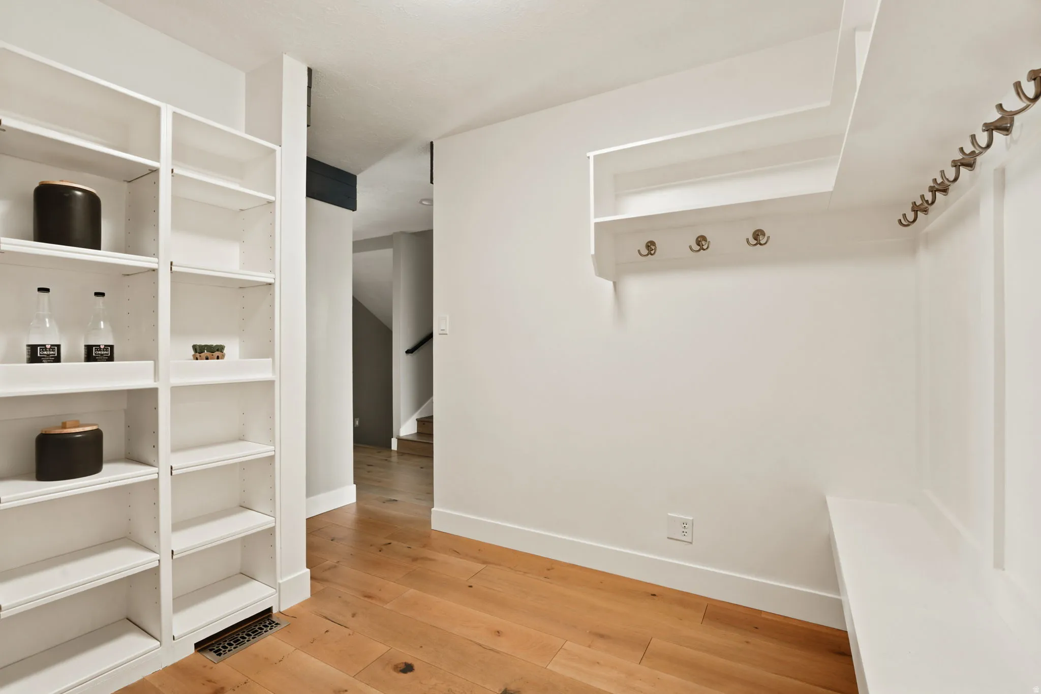 Entryway featuring wood-finish flooring, built-in shelving, integrated coat hooks, and a built-in bench