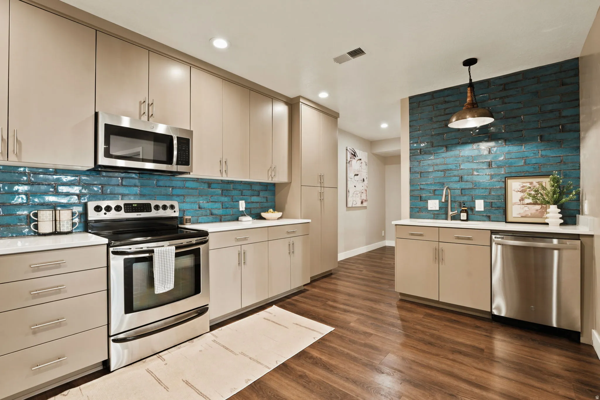 Kitchen featuring a vibrant blue subway tile backsplash, stainless steel appliances, wood-finish flooring, recessed lighting, and a contemporary pendant light fixture
