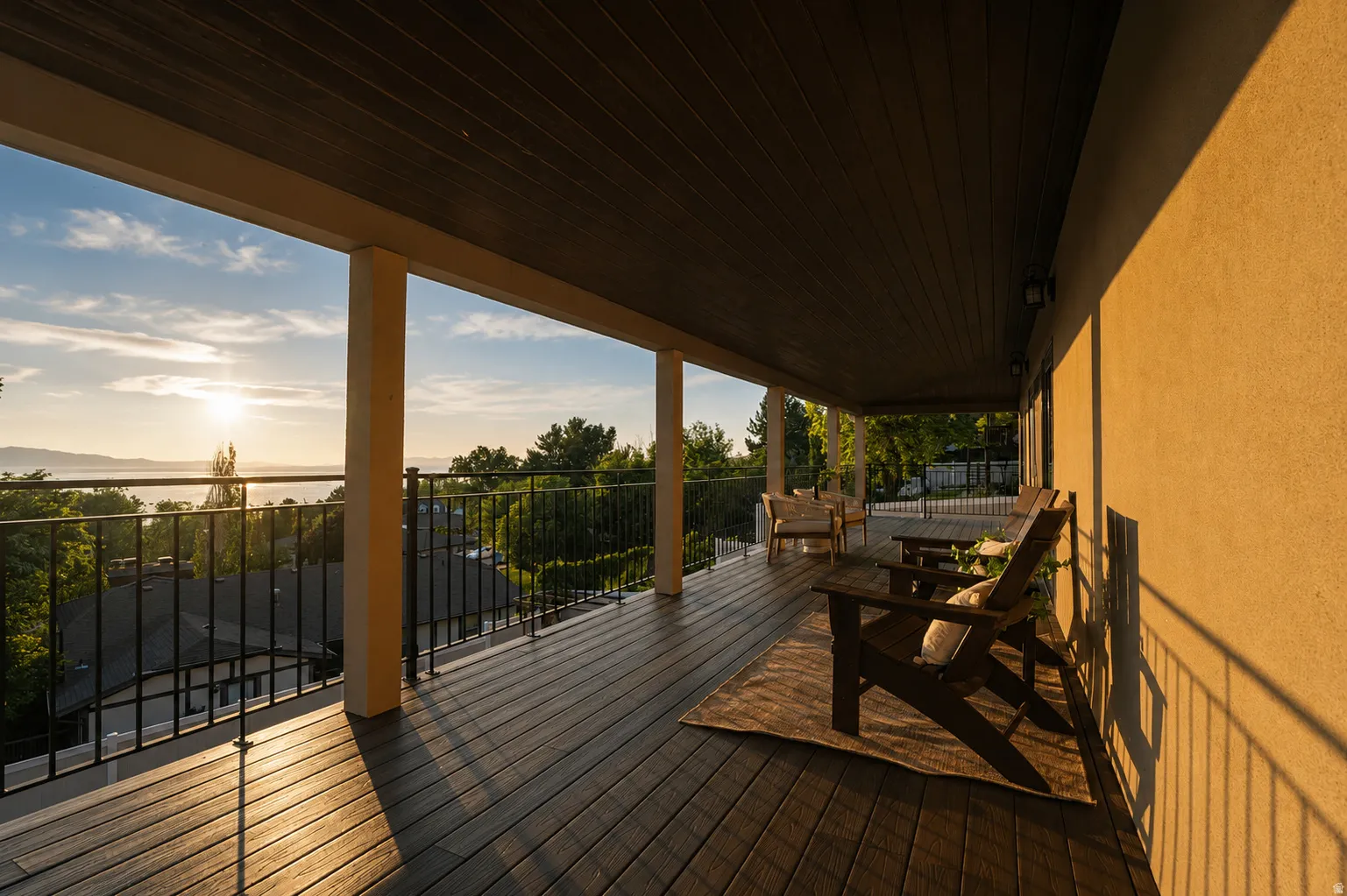 Expansive covered balcony featuring dark wood-finish decking, black metal railings, and a rich dark wood-paneled ceiling