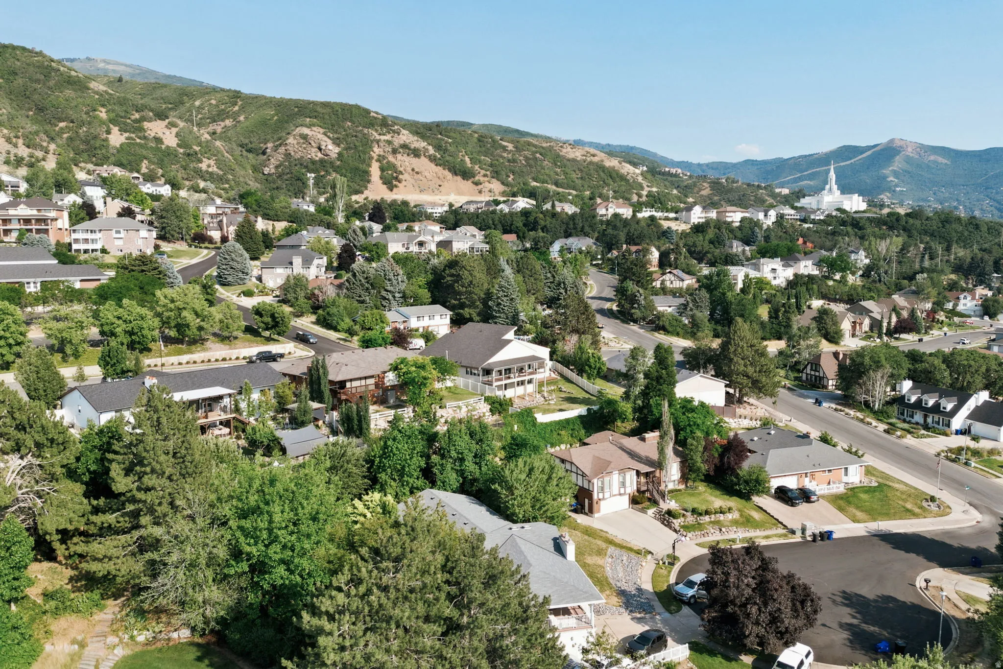 Neighborhood featuring mature trees, paved streets, and mountainous terrain
