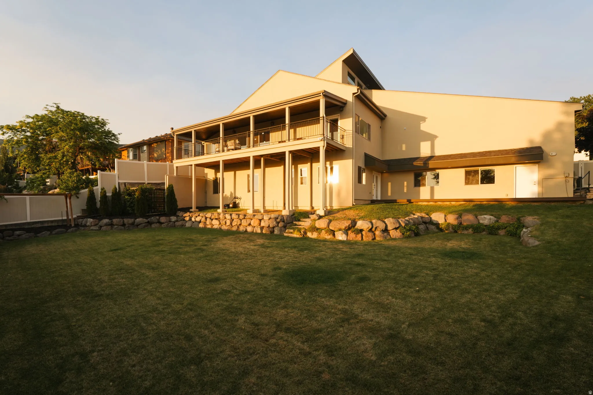 Expansive terraced backyard featuring a manicured lawn, established rock retaining walls, and mature landscaping