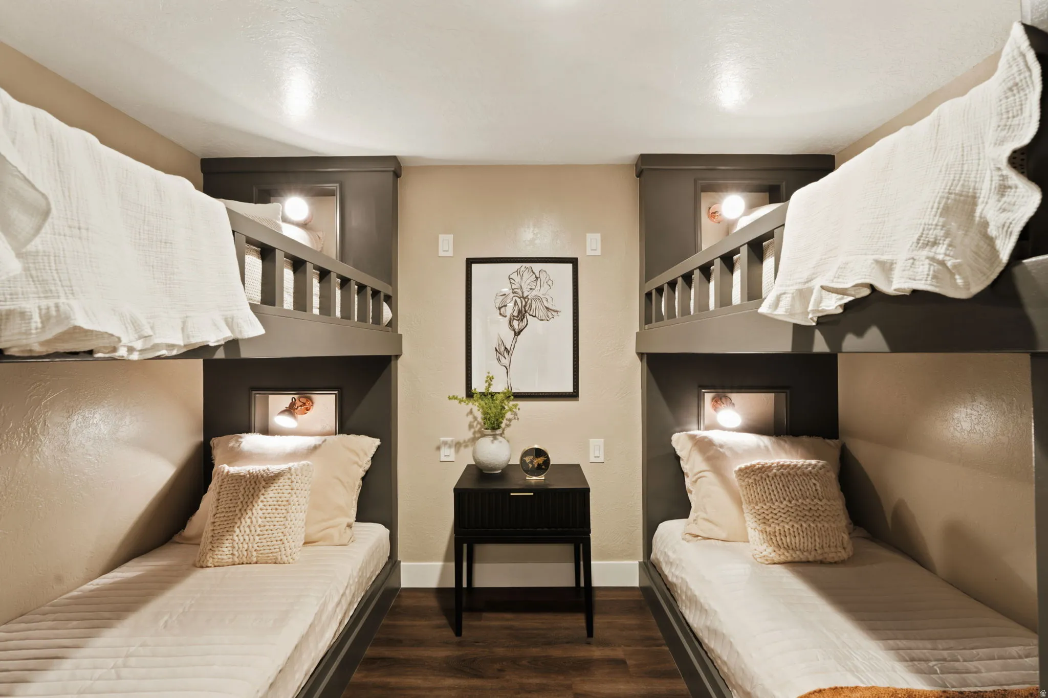 Custom-built bunk beds with integrated lighting, wood-finish flooring, and a central nightstand feature