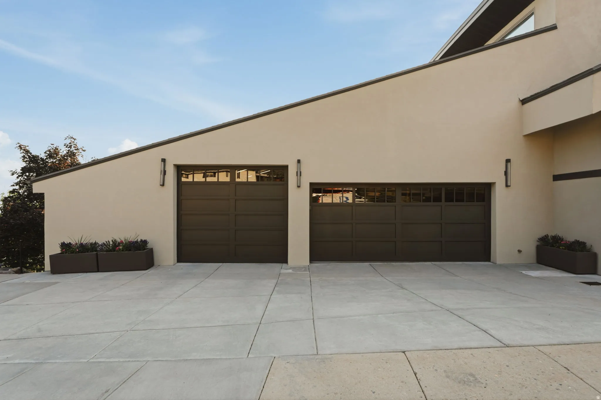 Stucco exterior with two dark paneled garage doors featuring upper window inserts