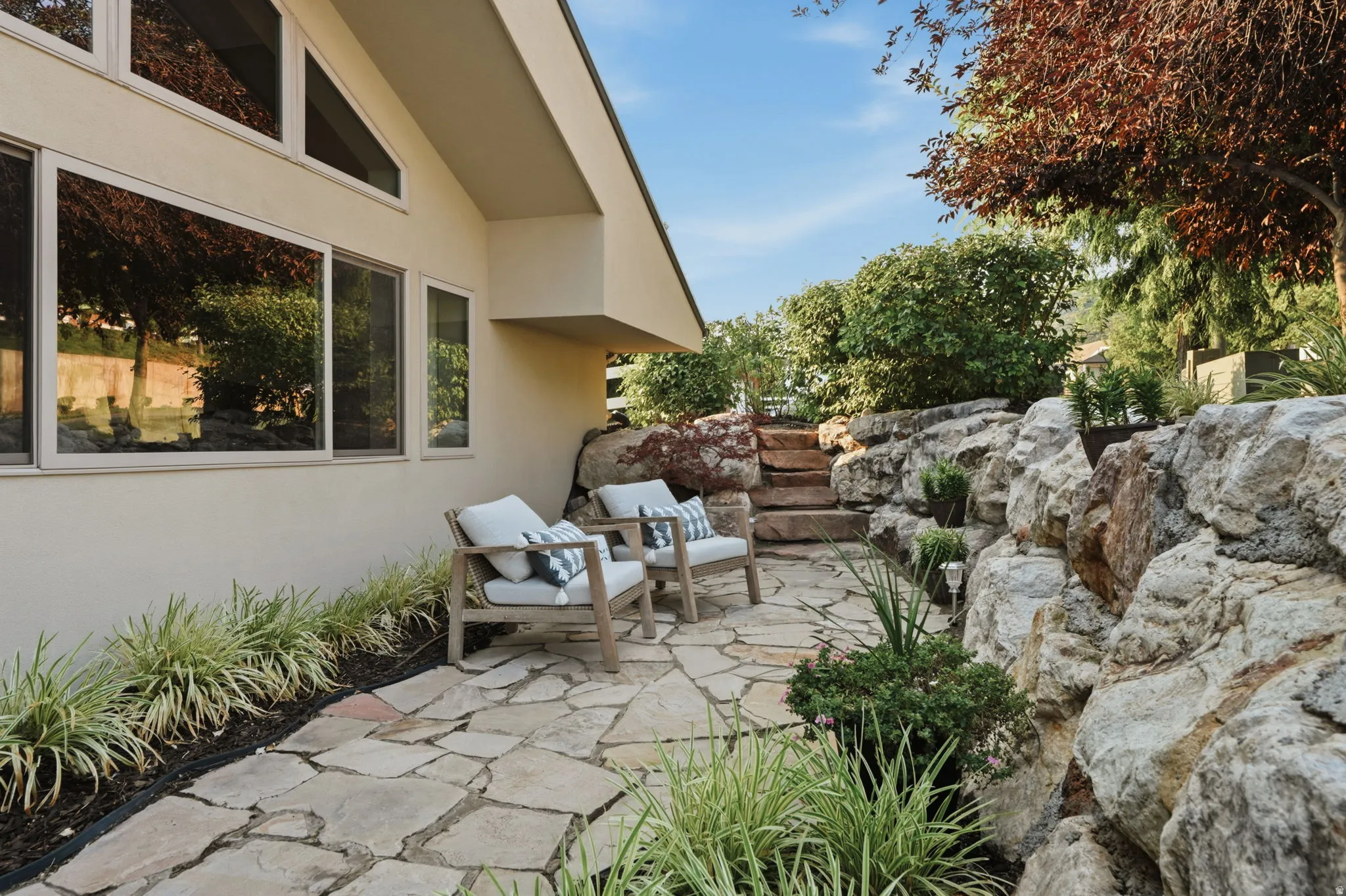 Stone patio featuring natural flagstone paving, a rock retaining wall, and integrated landscaping