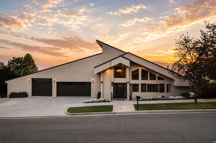 Contemporary exterior featuring a distinctive sloped roofline, dual garage doors, and a prominent entry with transom window