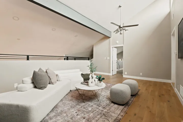 Living area featuring vaulted ceilings, wood-finish flooring, and a modern ceiling fan