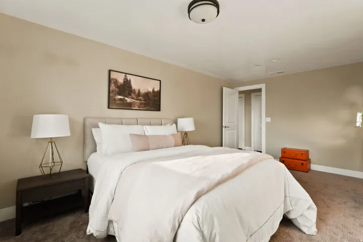 Bedroom featuring a light-colored upholstered headboard, neutral wall paint, and gray carpet flooring