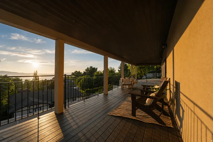 Expansive covered balcony featuring dark wood-finish decking, black metal railings, and a rich dark wood-paneled ceiling