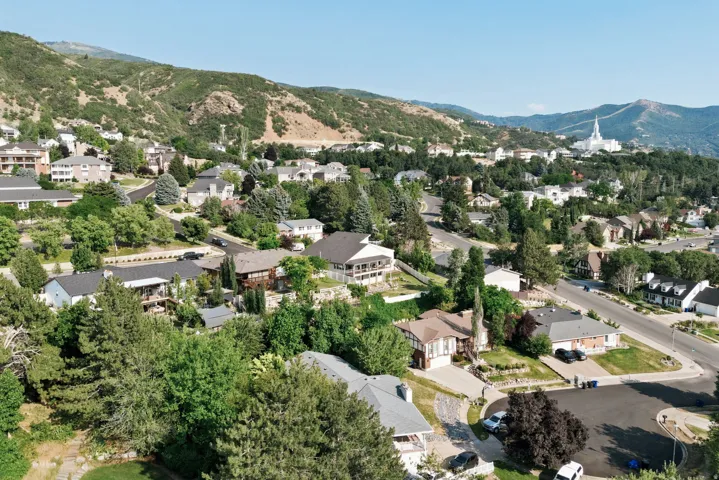 Neighborhood featuring mature trees, paved streets, and mountainous terrain