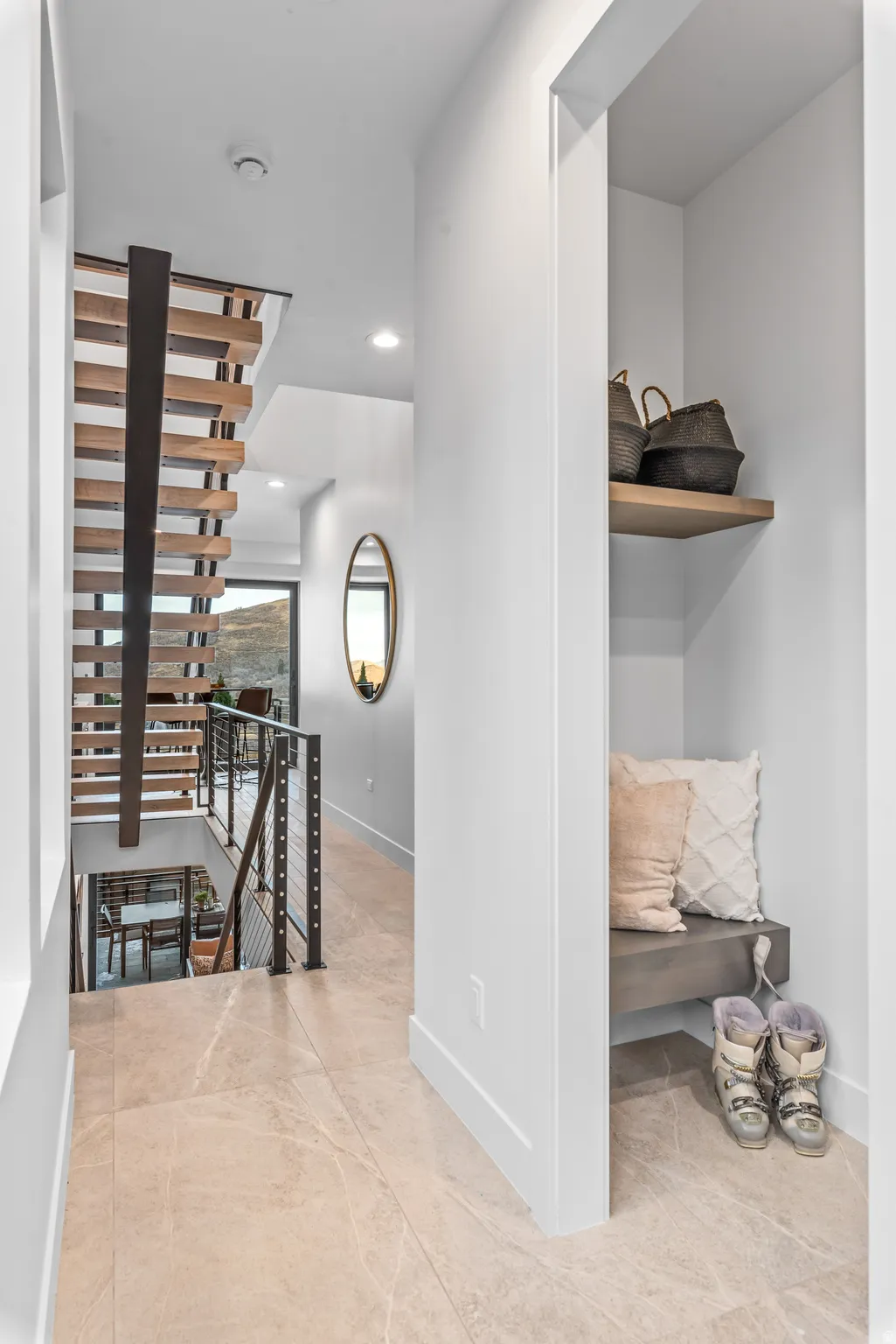 Hallway featuring large format tile flooring, a built-in bench with a floating shelf, and a modern open-tread staircase with metal railings