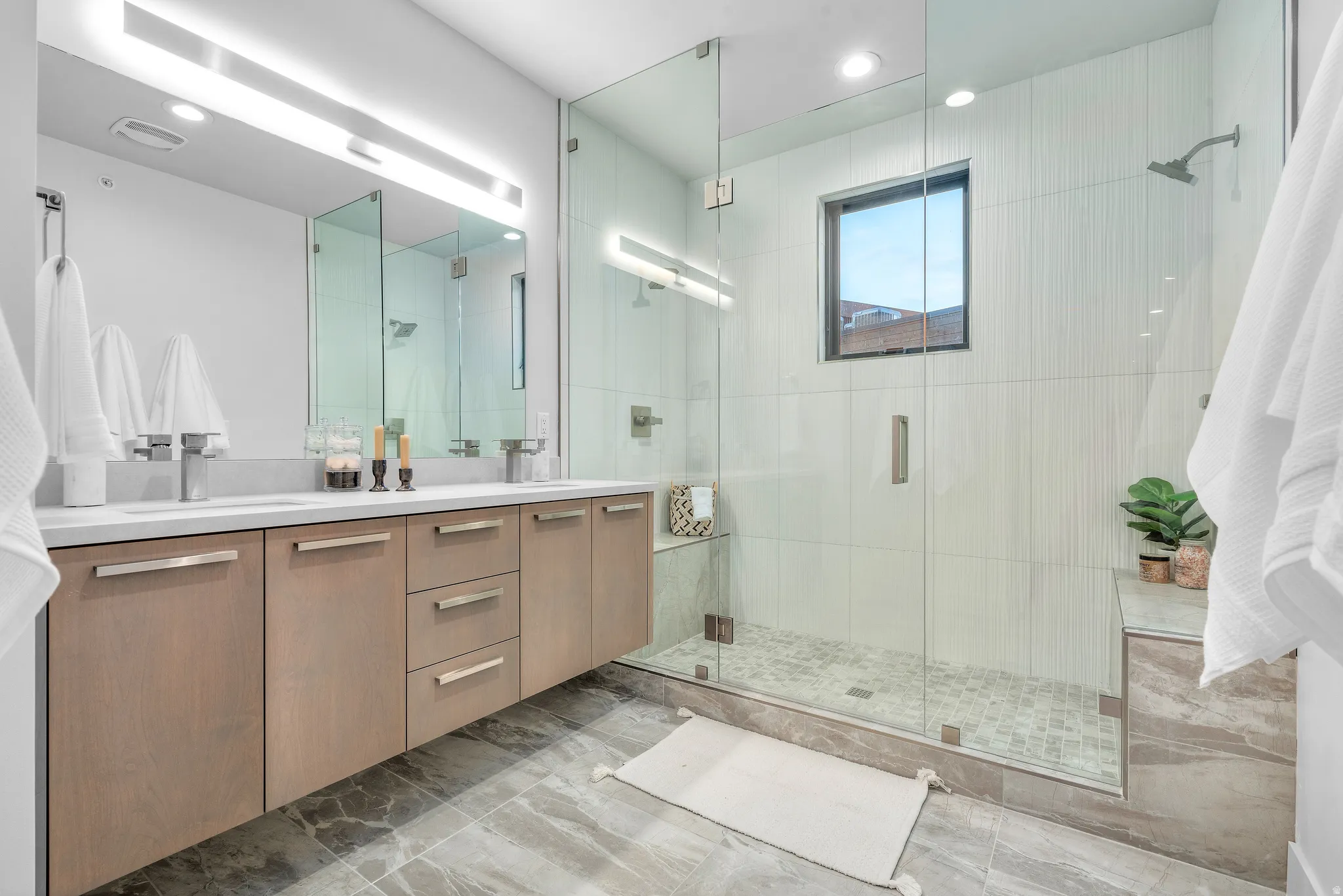 Contemporary bathroom featuring a floating dual vanity with light wood-finish cabinetry and chrome fixtures