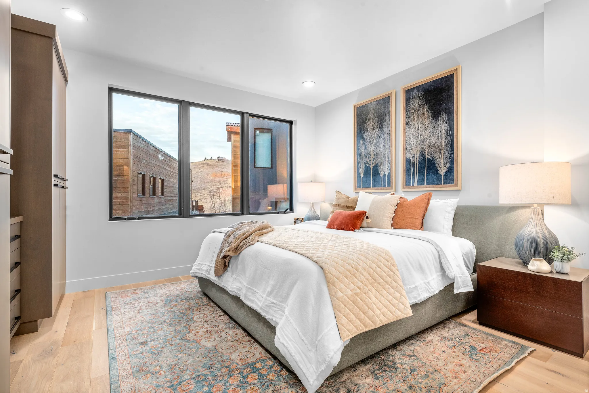 Bedroom featuring light wood-finish flooring and a large window with black framing