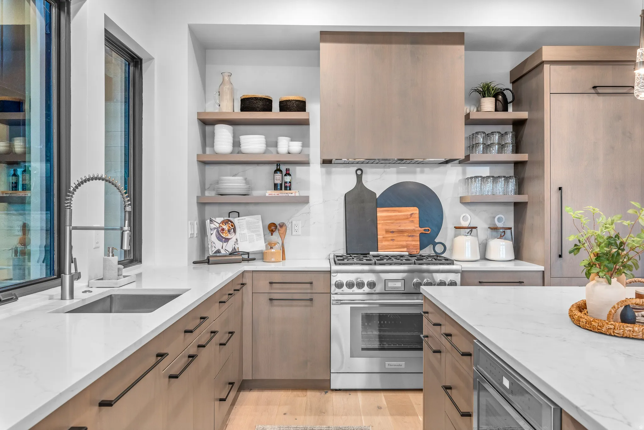 Contemporary kitchen featuring light wood-finish cabinetry, white countertops, and a stainless steel range with a coordinating hood
