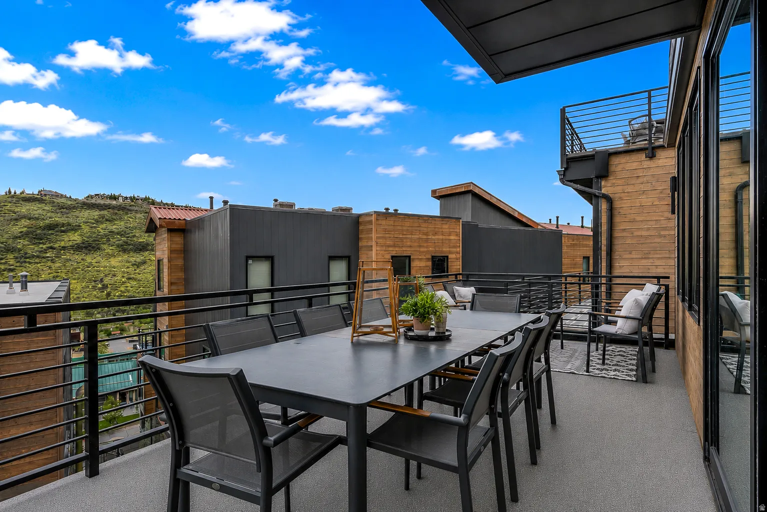 Expansive outdoor deck featuring a gray surface, black metal railings, and a partial awning